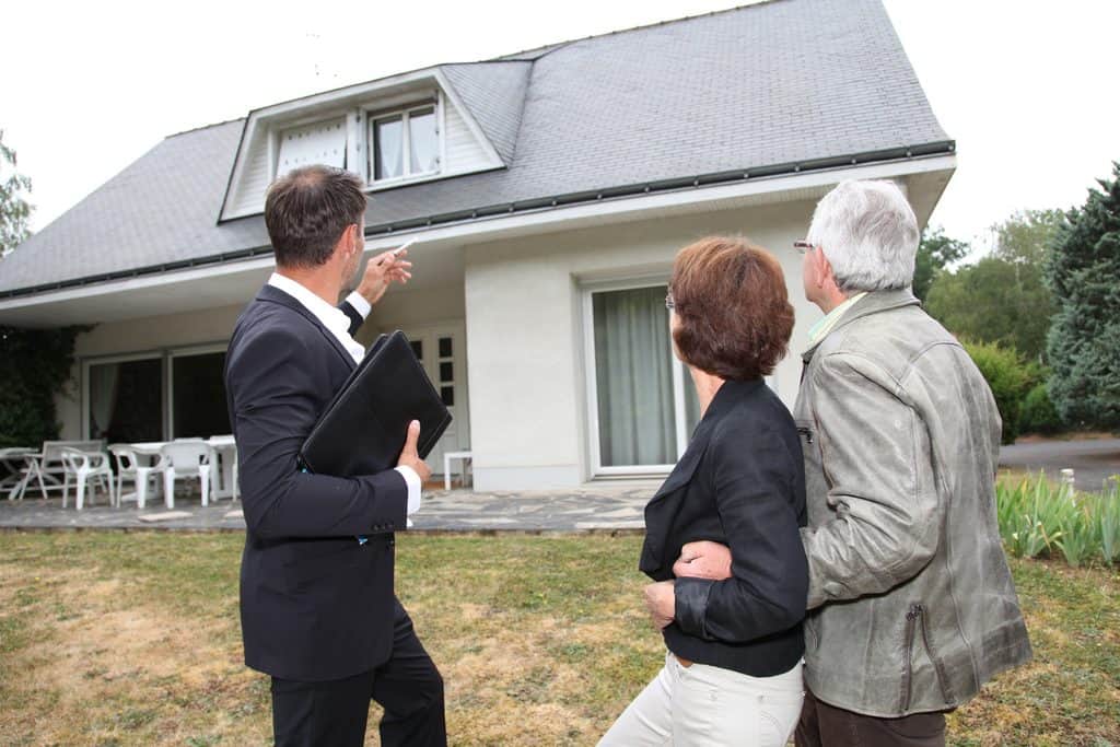 Public Insurance Claims Adjuster with senior couple assessing a home.